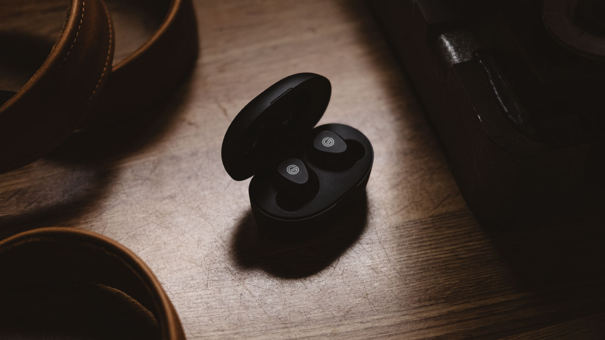Photo of the GT220 headphones in their case sitting on a dark wooden floor